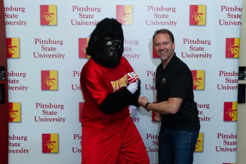 Gus the Gorilla and an attendee from Amazon pumping arms for CHECK!