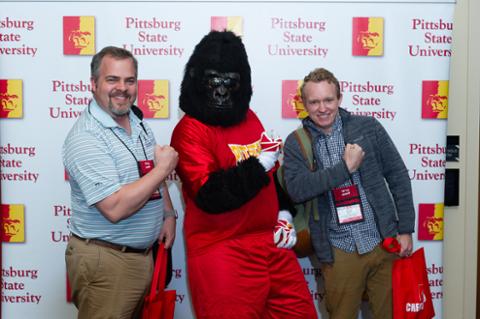 Gus the Gorilla and two men pumping their arms for CHECK!