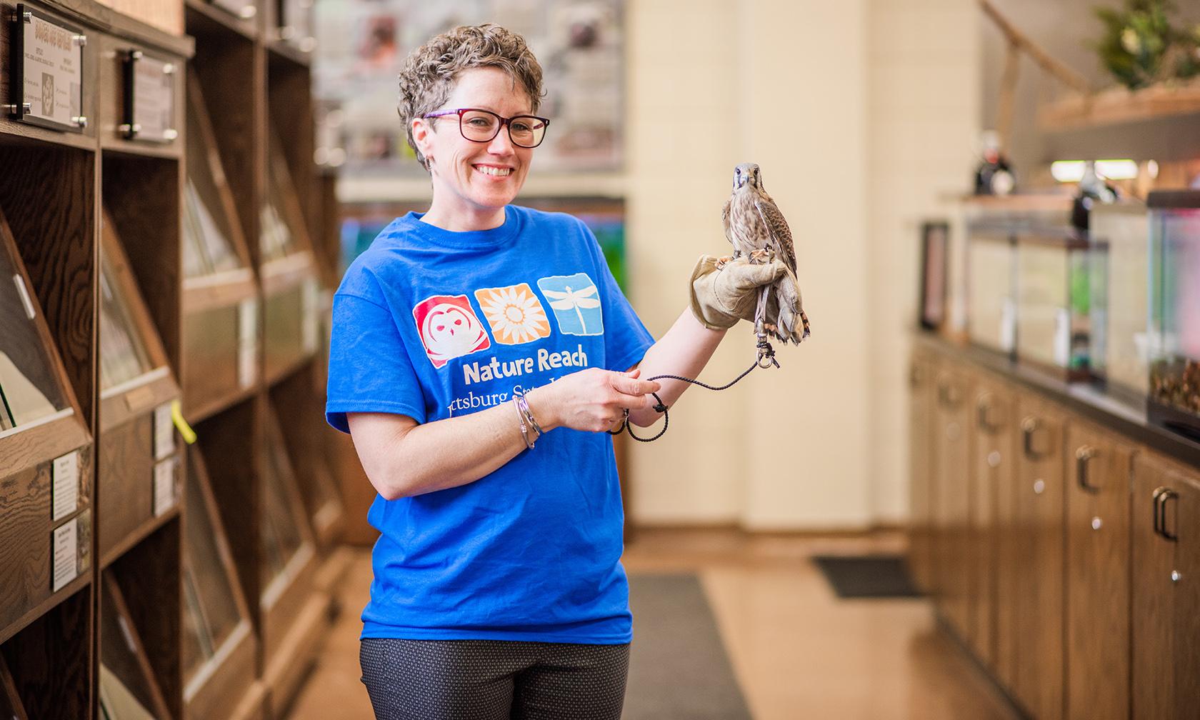 Biology student in Nature Reach shirt with American kestrel perched on her hand