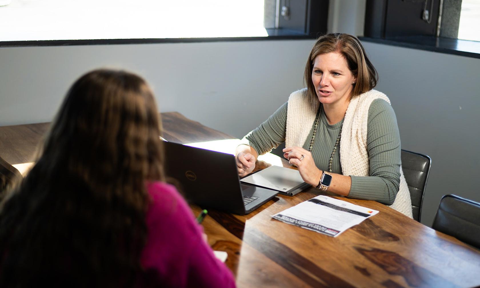 A business counselor talking with a client at a laptop