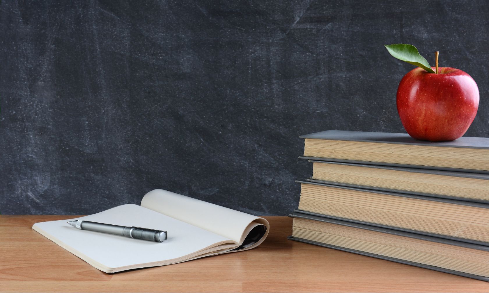 Apple on a stack of books on a desk.