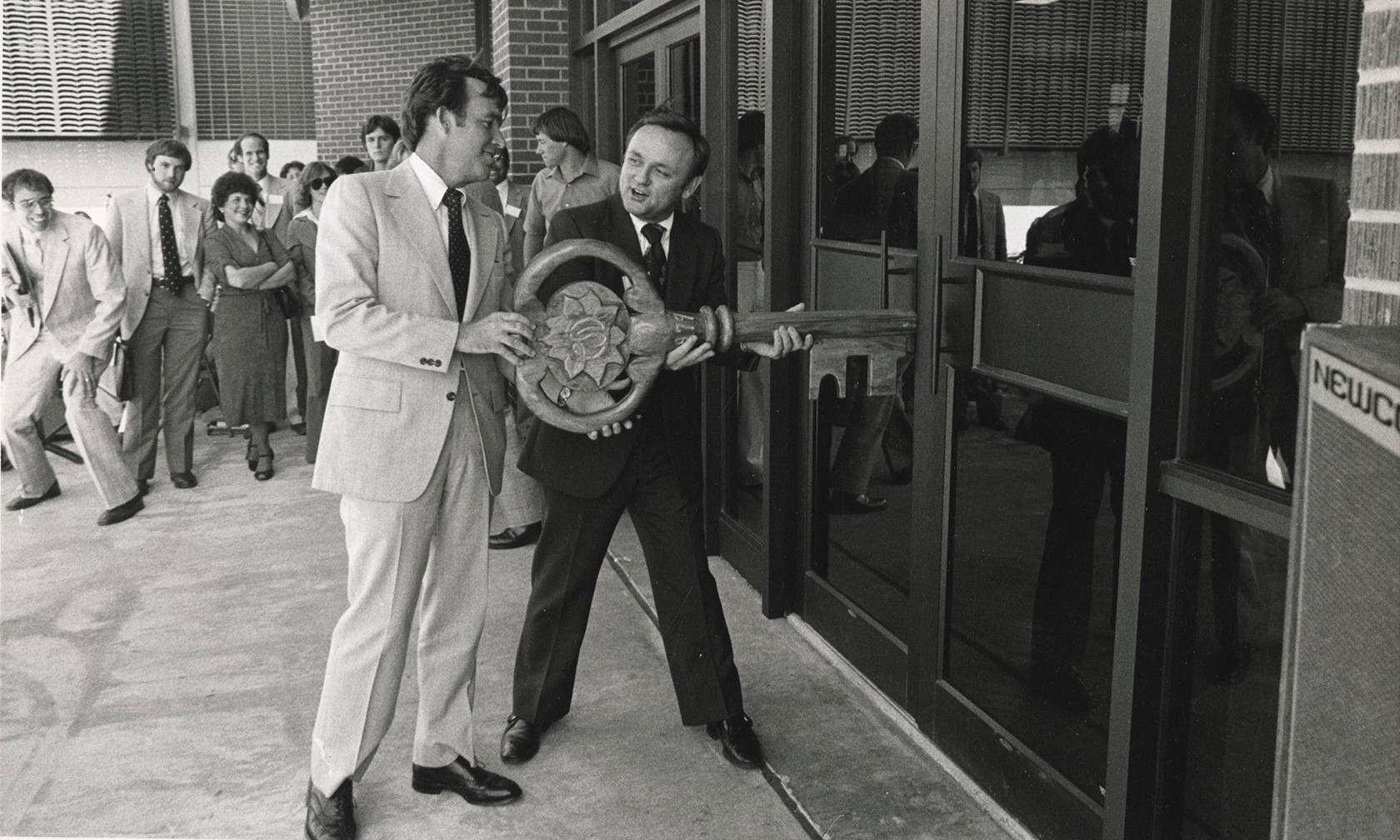 Two men with large key pretending to unlock door to new library