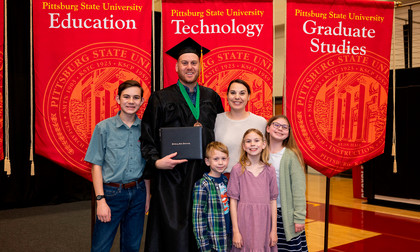 Graduate in cap and gown with his children and wife