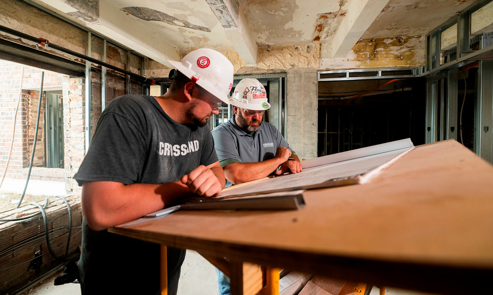 two men in hardhats looking at blueprints