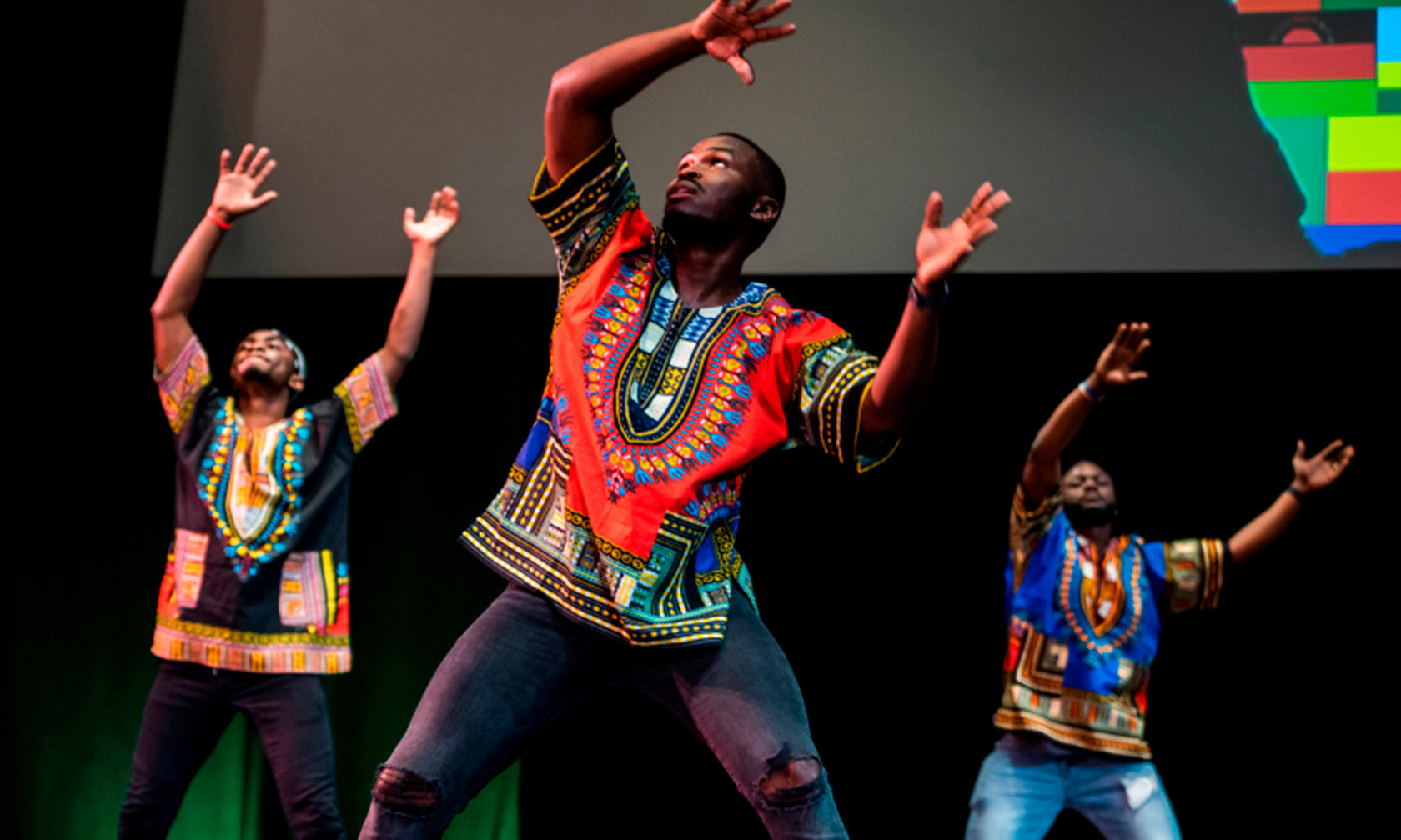 African students wear bright clothing from their country and culture, dancing on stage
