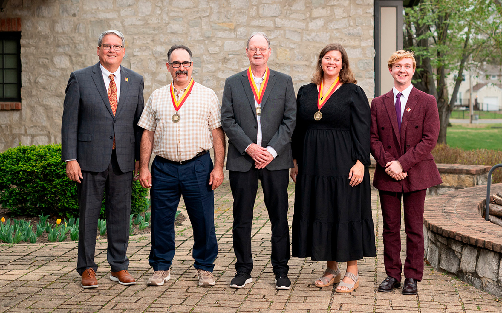 Faculty award recipients pose outside the presidential home with president newsom and Charlie