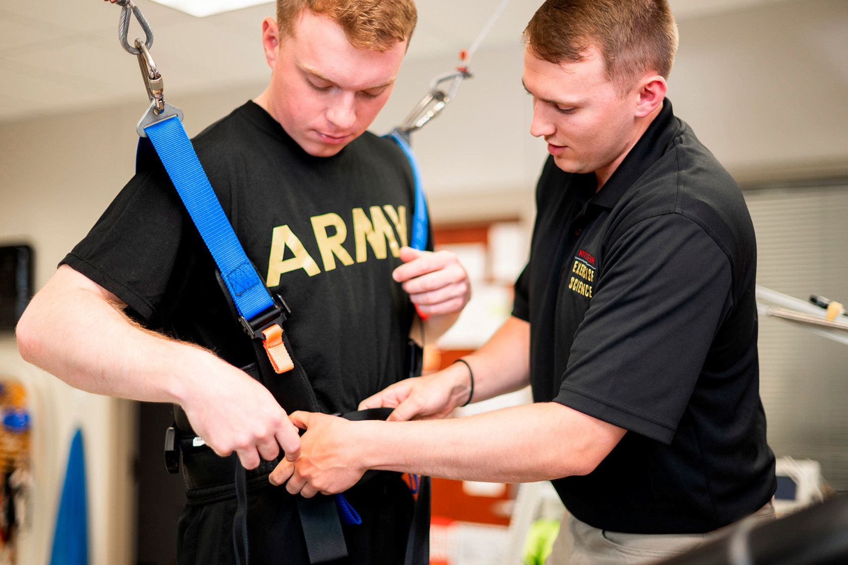 Austin helps a man in a harness walk on a treadmill