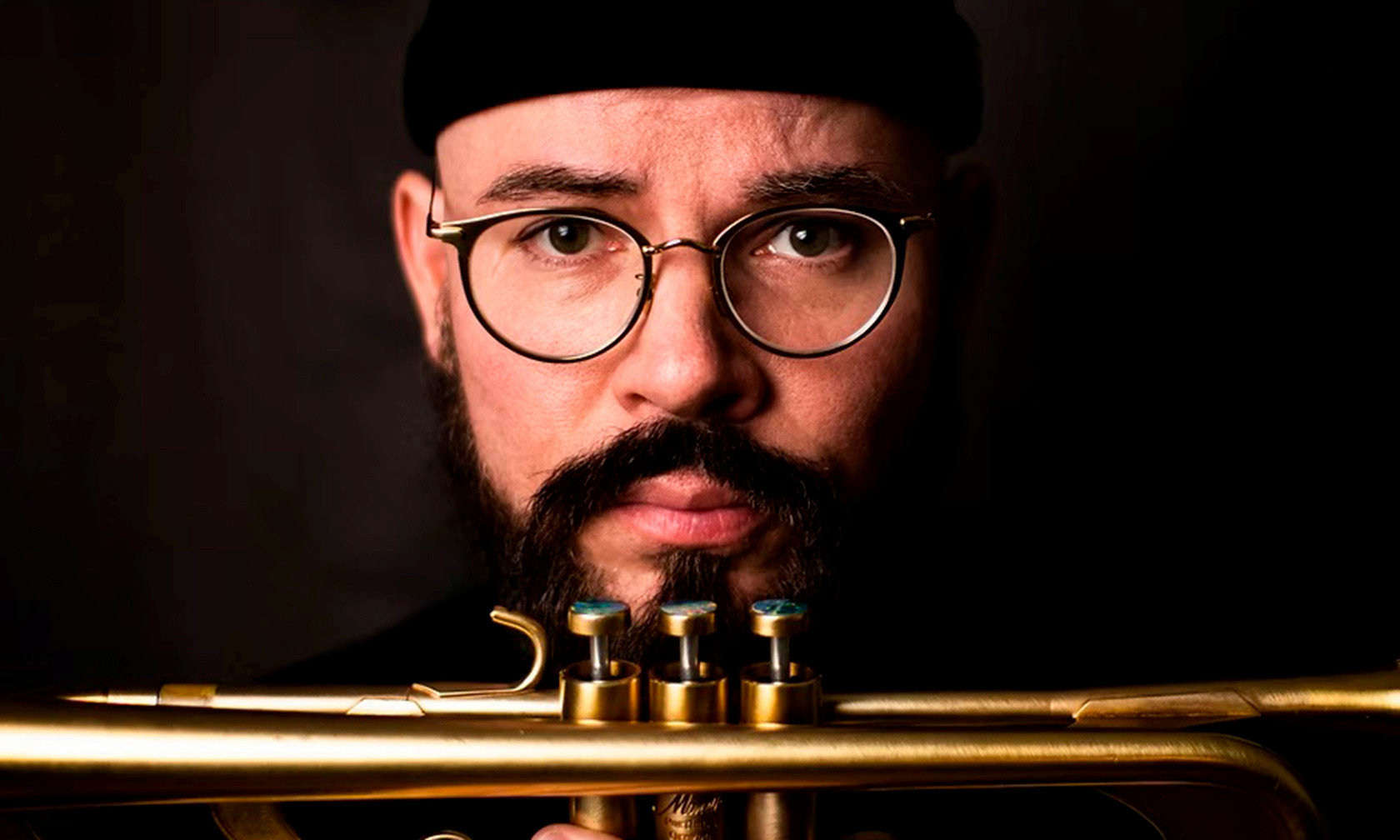man looking at camera with trumpet beneath his chin